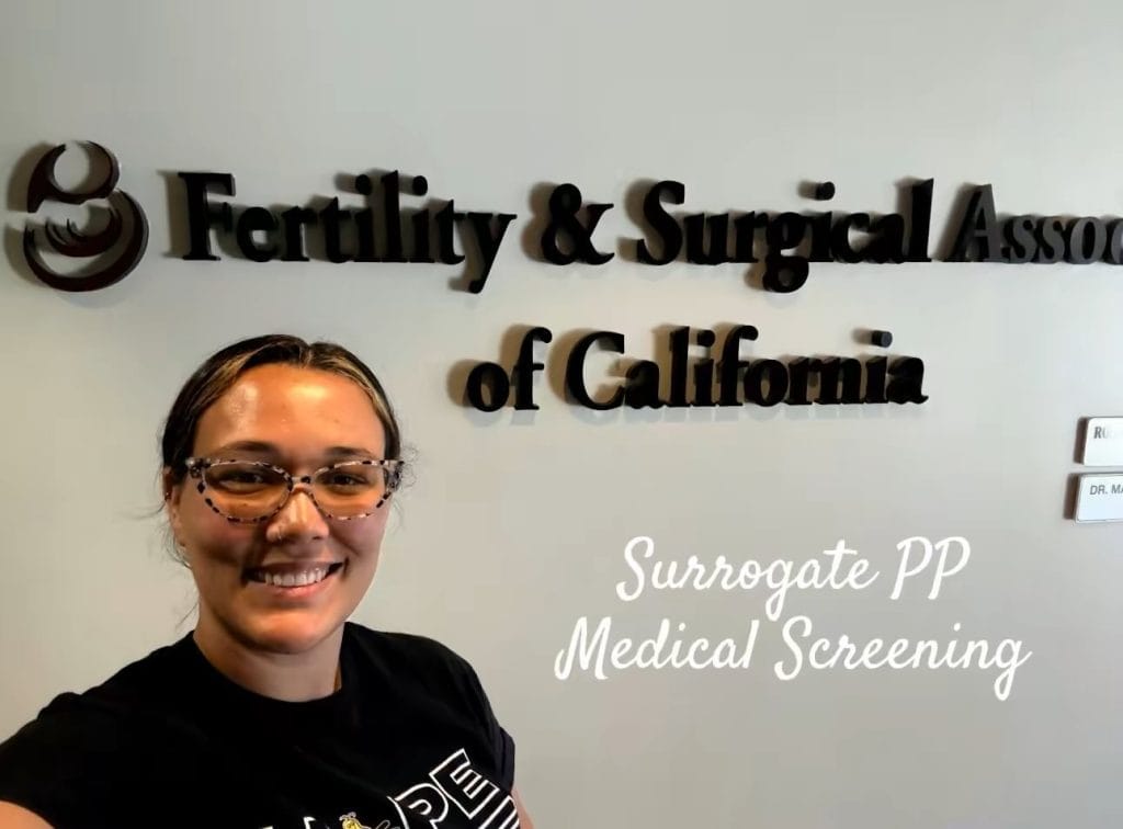 A happy person stands in front of a clinic sign, representing Babytree Surrogacy’s medical screening for surrogates. Alt text: Person at clinic showing Babytree Surrogacy medical screening for surrogates. A happy person stands in front of a clinic sign, representing Babytree Surrogacy’s medical screening for surrogates. Alt text: Person at clinic showing Babytree Surrogacy medical screening for surrogates.